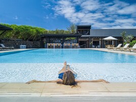 Una piscina al aire libre, sombrillas, sillones reclinables de piscina
