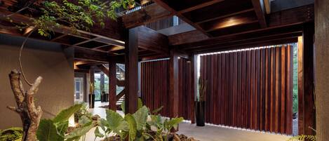 A modern interior with wooden beams, a concrete floor, and potted plants.
