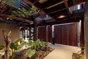 Un interior moderno con vigas de madera, suelo de hormigón y plantas en macetas.
