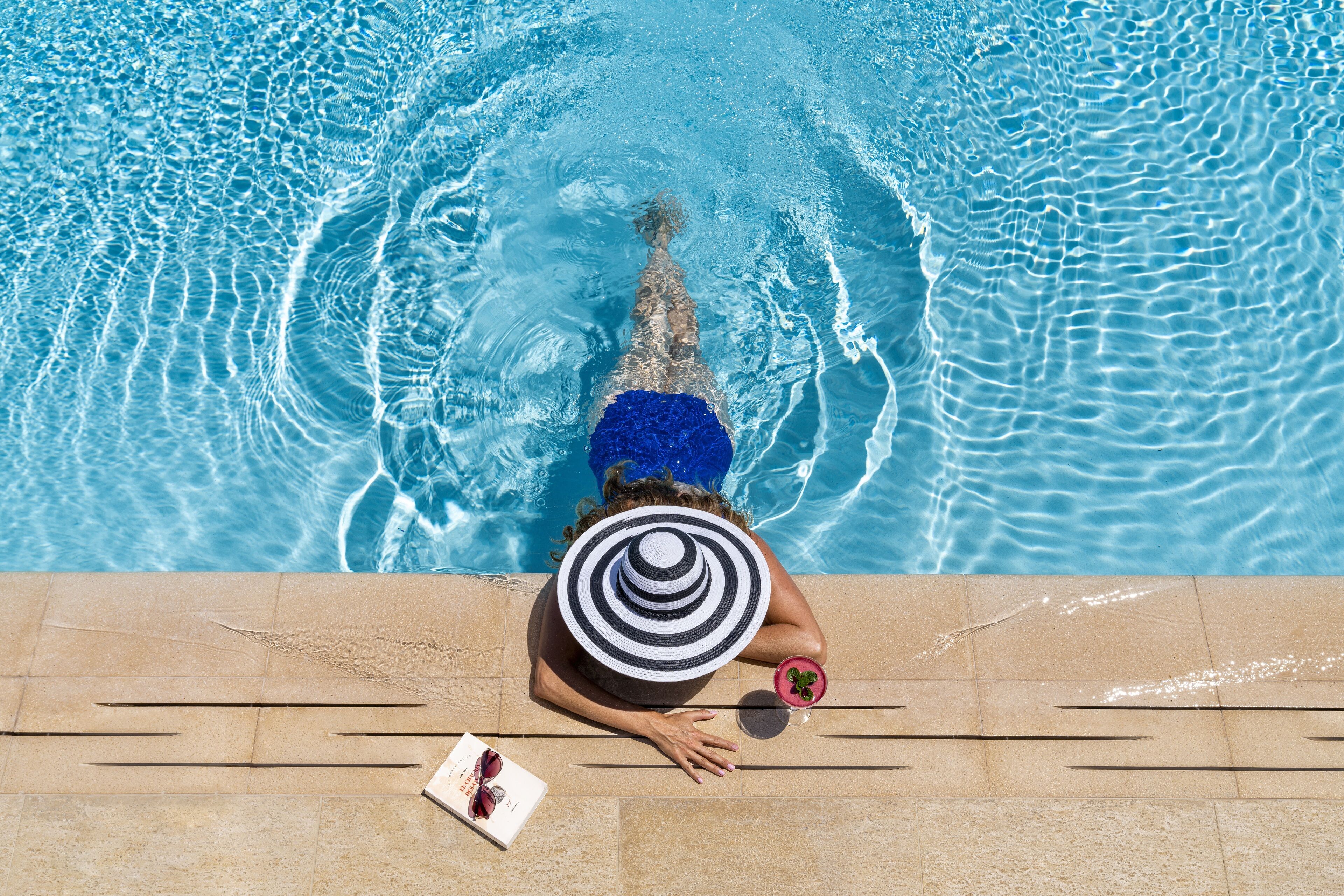 A person swimming in a pool with clear blue water.