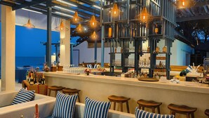 A bar area with seating, a bar counter, and hanging pendant lights.