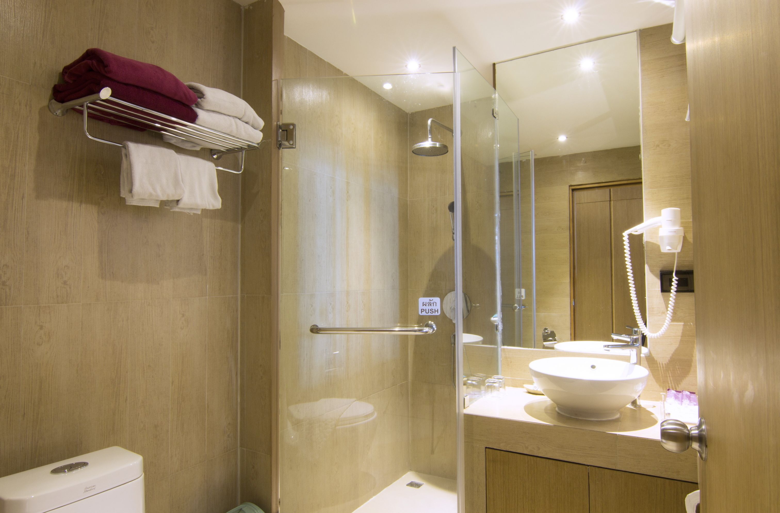 A modern bathroom with a glass-enclosed shower, a white sink, and a towel rack with a red towel.