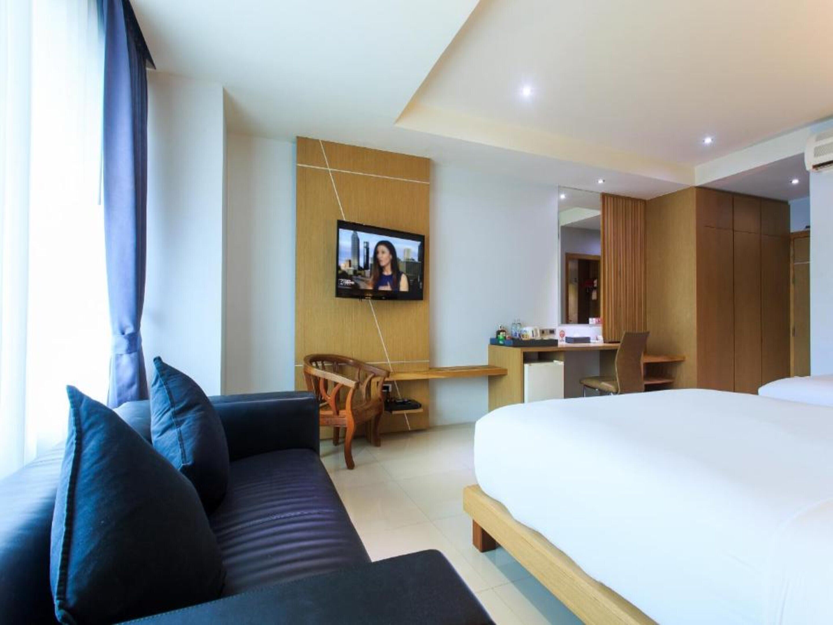 Una habitación de hotel con cama, sofá, escritorio y televisión.