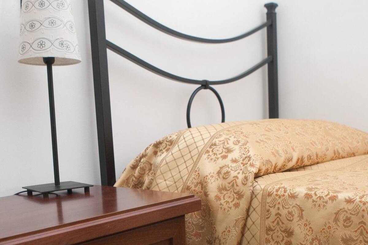 A bedroom with a bed, a nightstand, and a lamp.