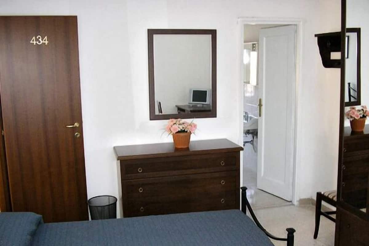 A bedroom with a bed, dresser, mirror, and a door labeled 434.