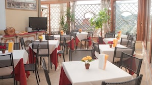 Un restaurant avec des tables dressées pour le service, un téléviseur et des plantes en pot.