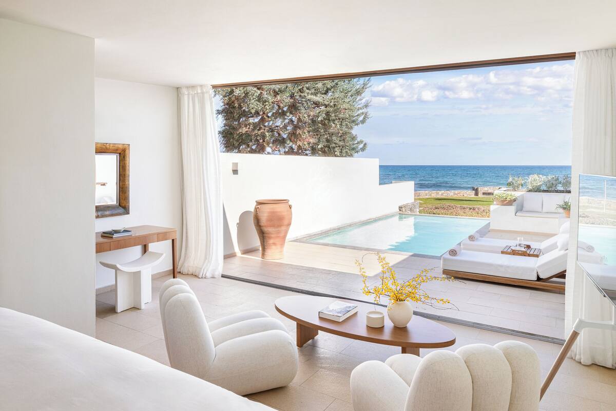 Ein modernes Zimmer mit Sofa, Stühlen, einem Tisch und Meerblick.