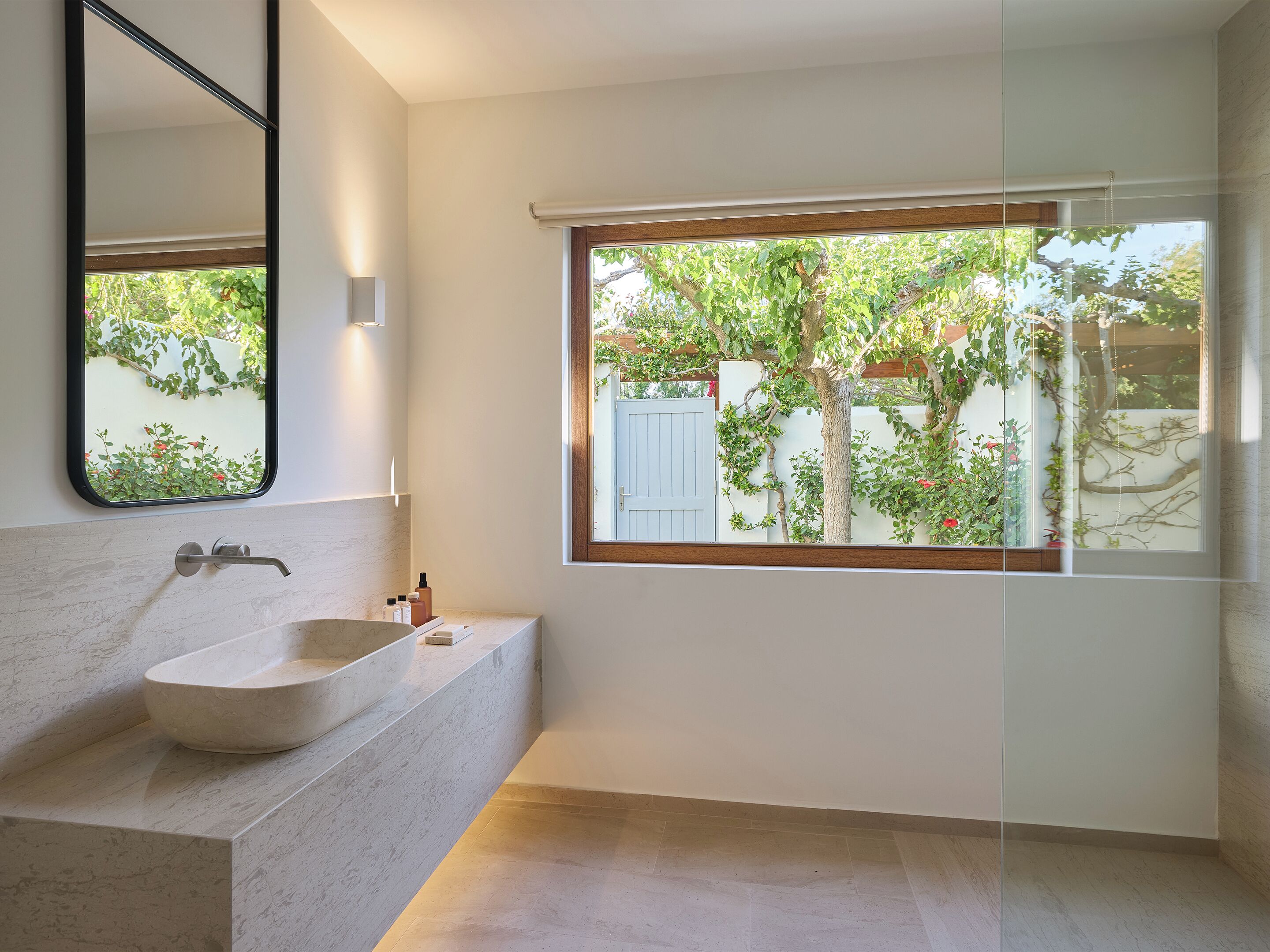 Un baño moderno con un ventanal grande, un lavabo de mármol y un espejo.