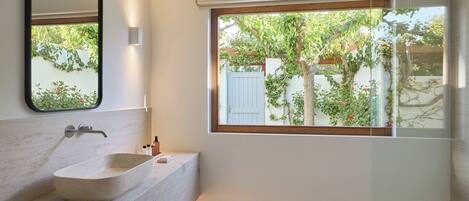 Un baño moderno con un ventanal grande, un lavabo de mármol y un espejo.