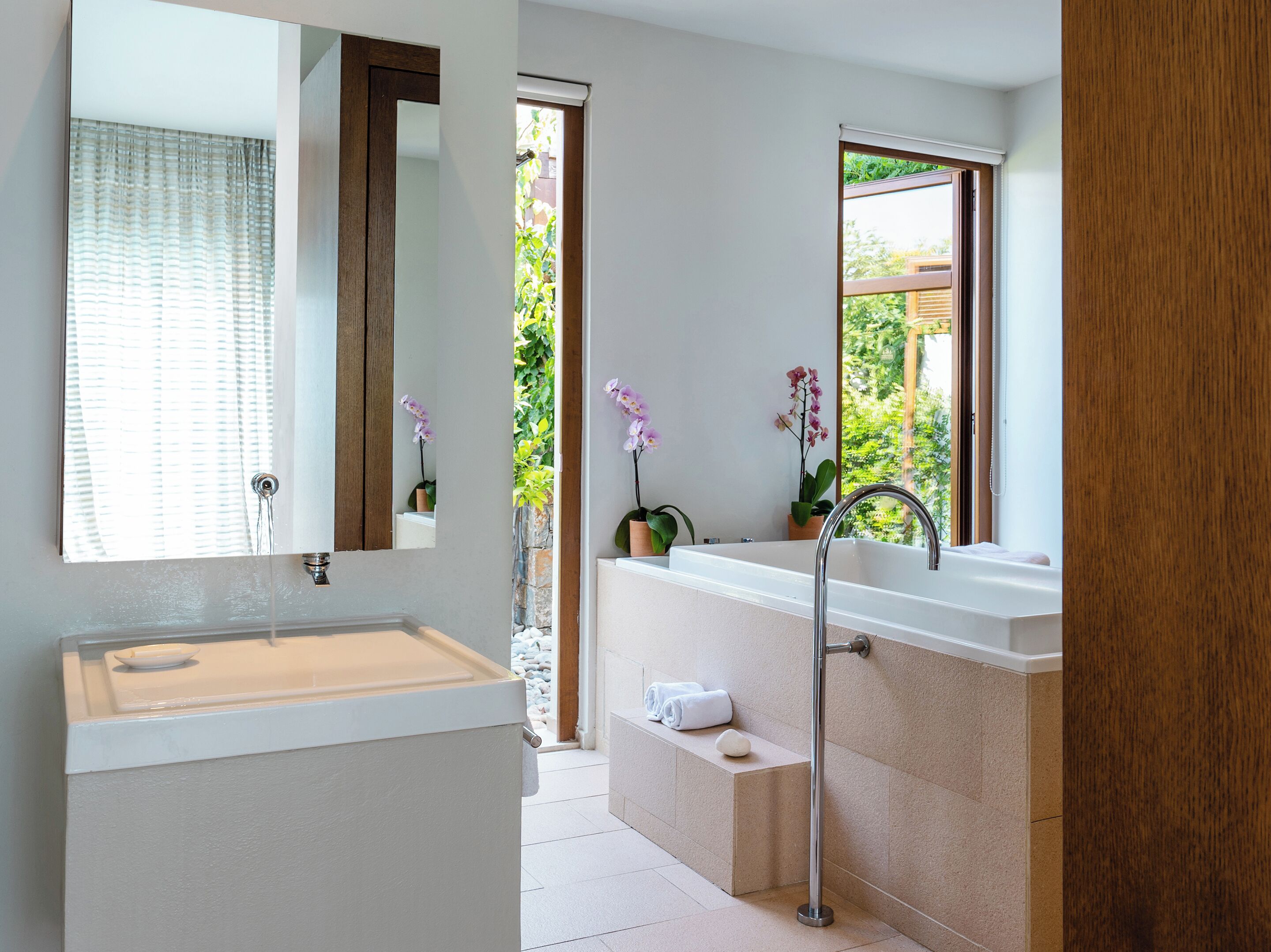 Un baño moderno con lavabo, espejo y ventana.