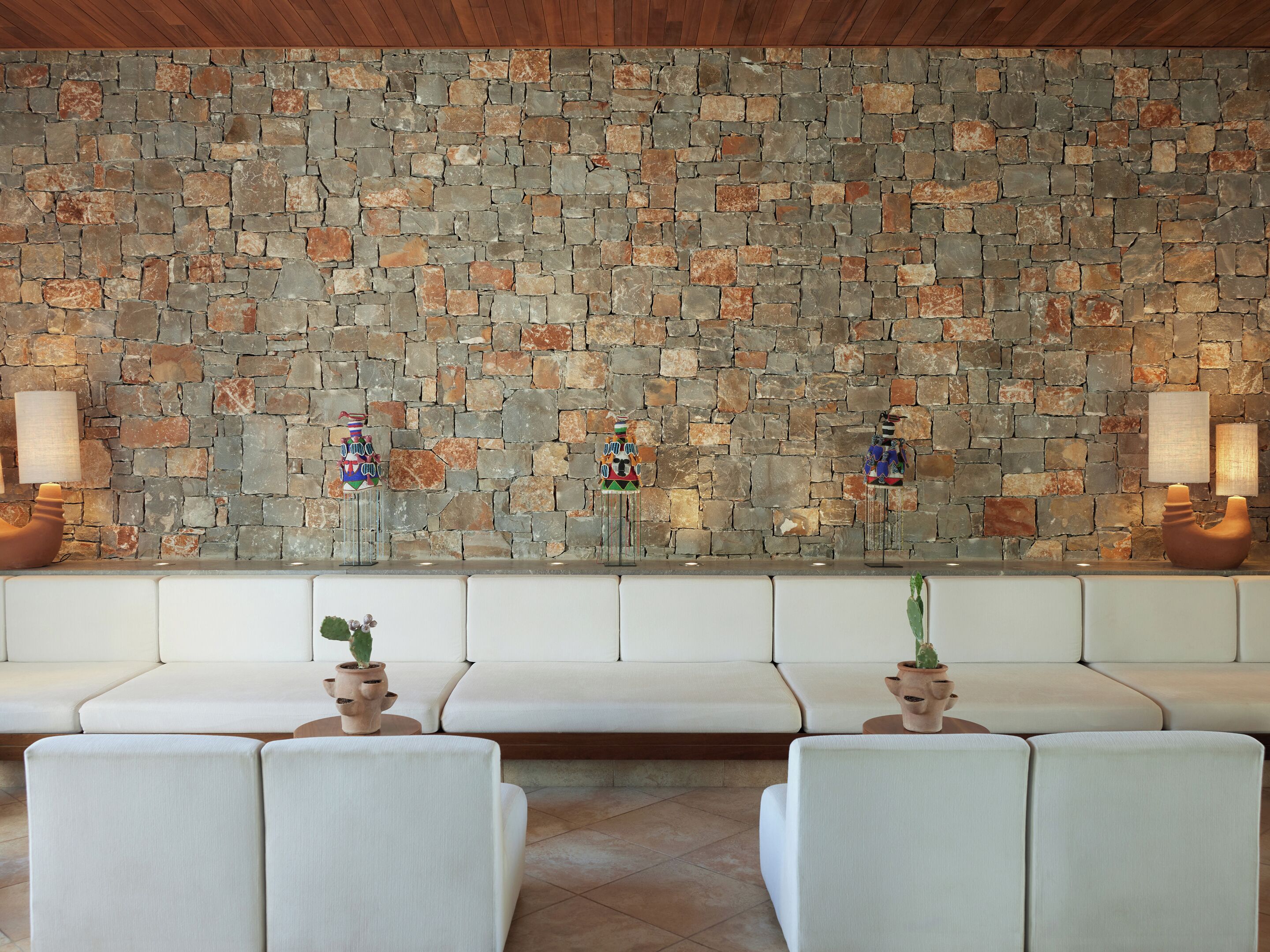 A stone wall with a bench and two lamps.