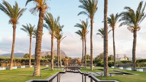 A landscaped area with palm trees and a reflective water feature. - Amirandes, A Resort to Live (Hersonissos)