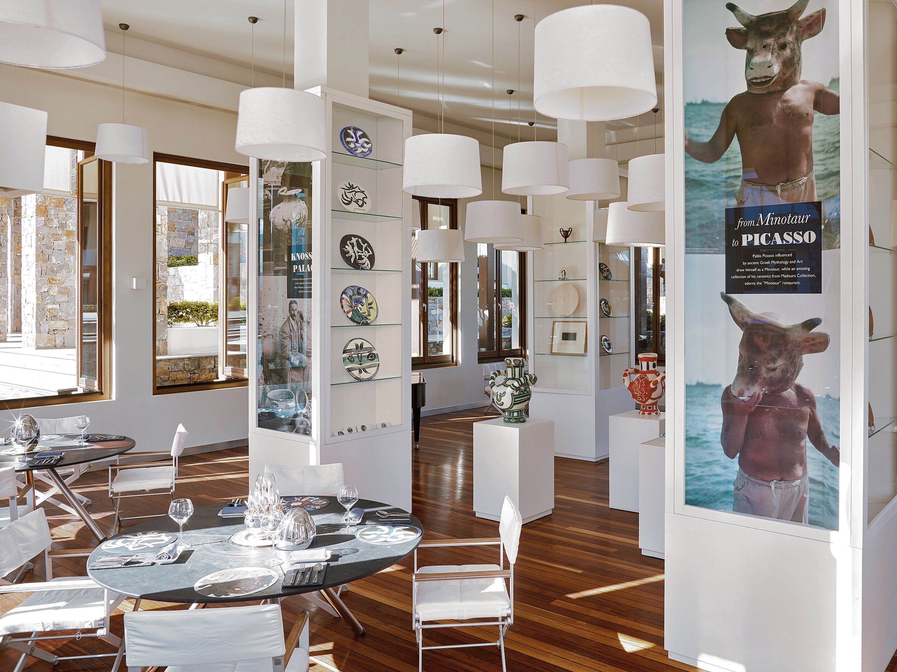 A modern interior with dining tables, chairs, and decorative plates on display.