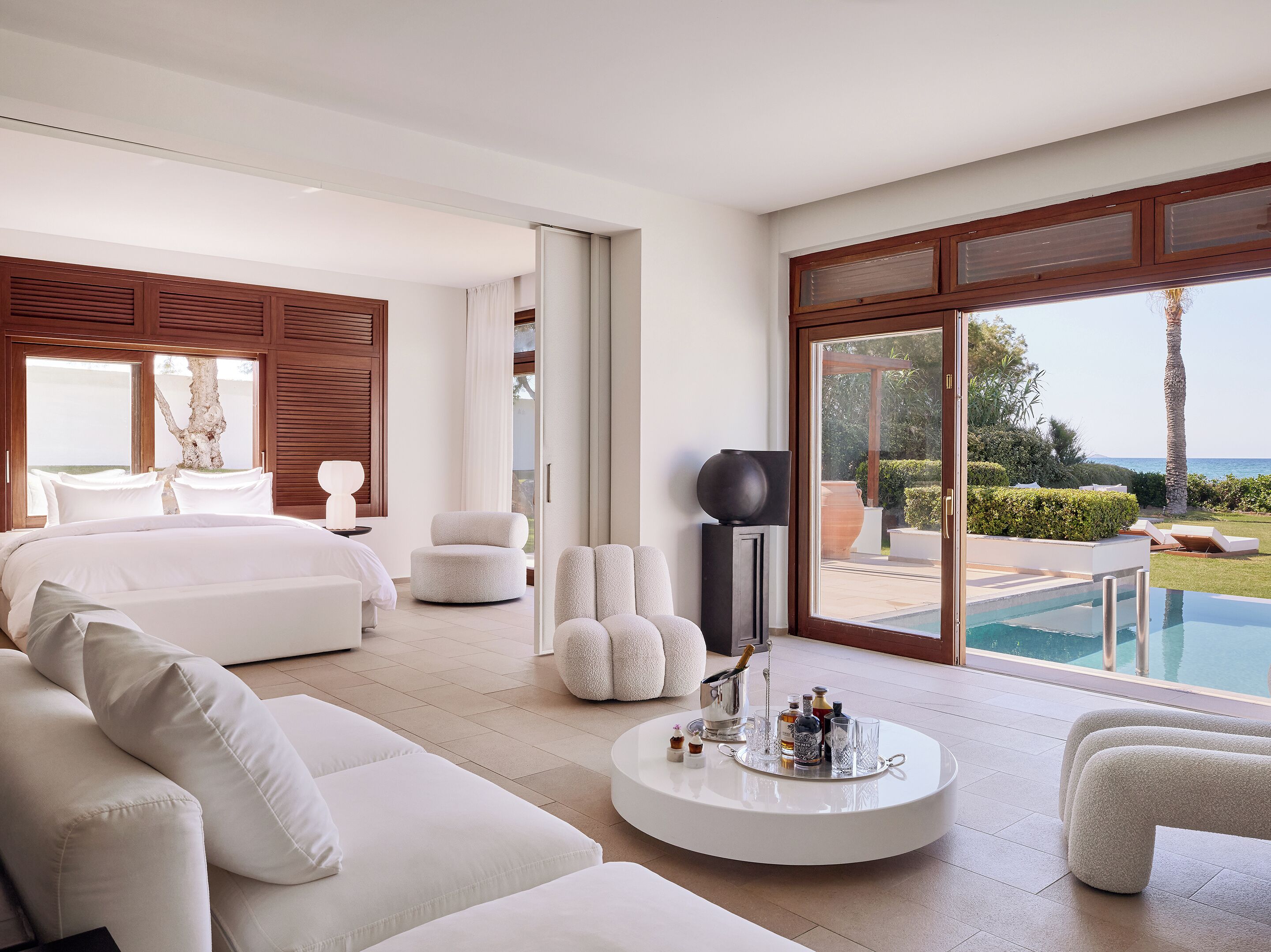 Une chambre d’hôtel moderne dotée d’un grand lit, d’un canapé, d’une télévision et offrant une vue sur la piscine.