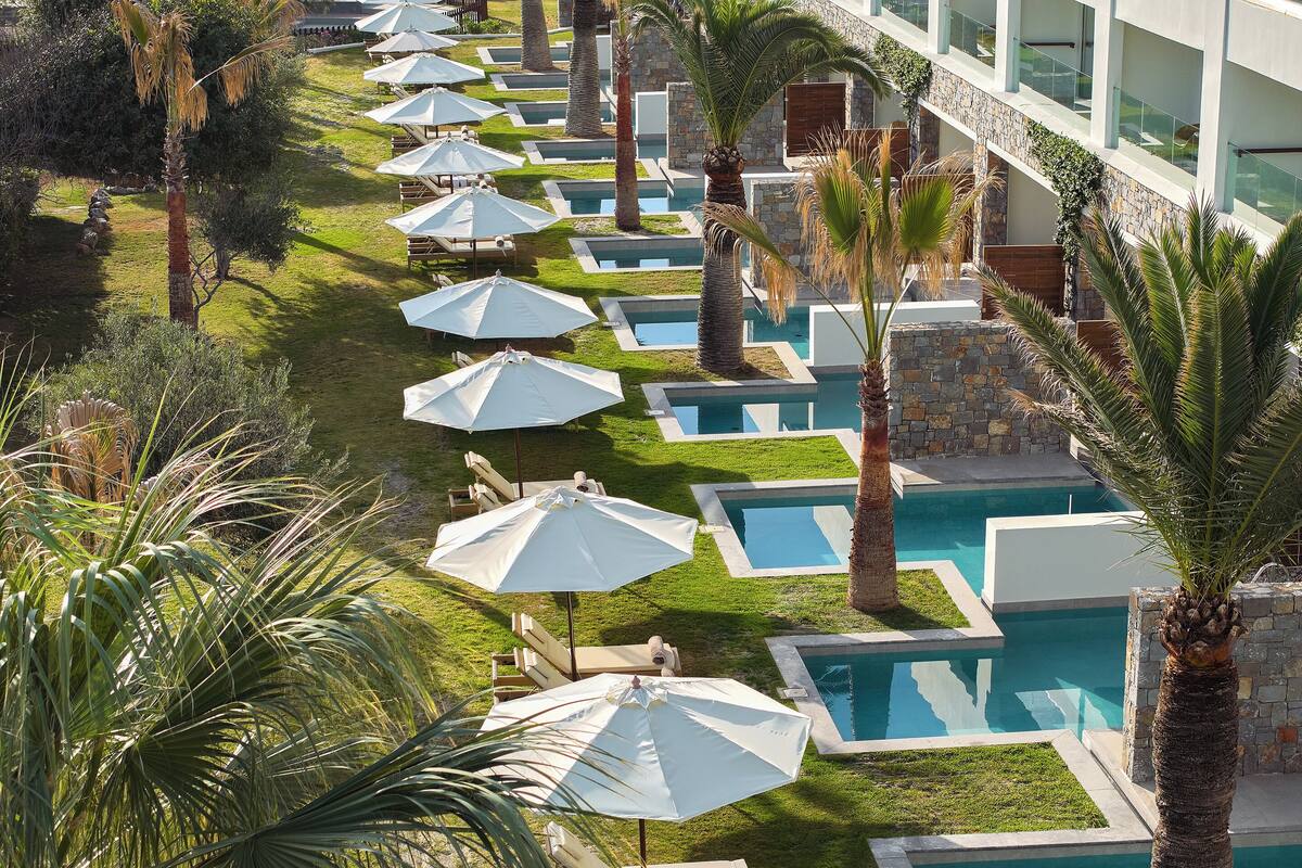 Ein Poolbereich mit mehreren kleinen Pools, Liegestühlen und Sonnenschirmen.