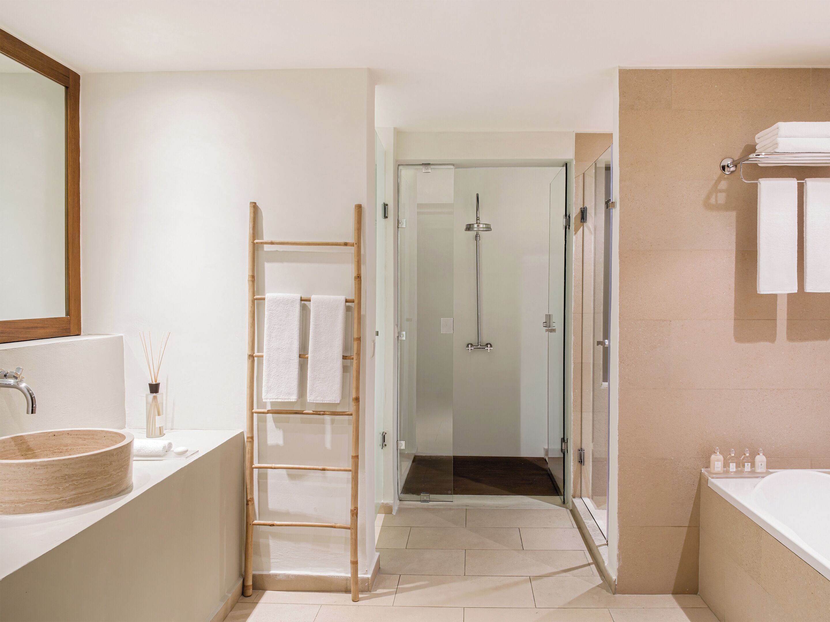 Un baño moderno con un espejo grande, una escalera de madera, una cabina de ducha de vidrio y una bañera.