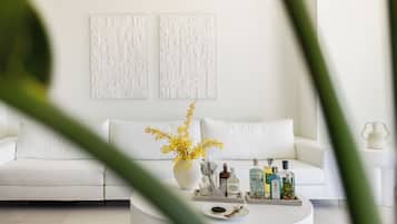 A modern living room with a white sofa, a coffee table with decorative items, and wall art.