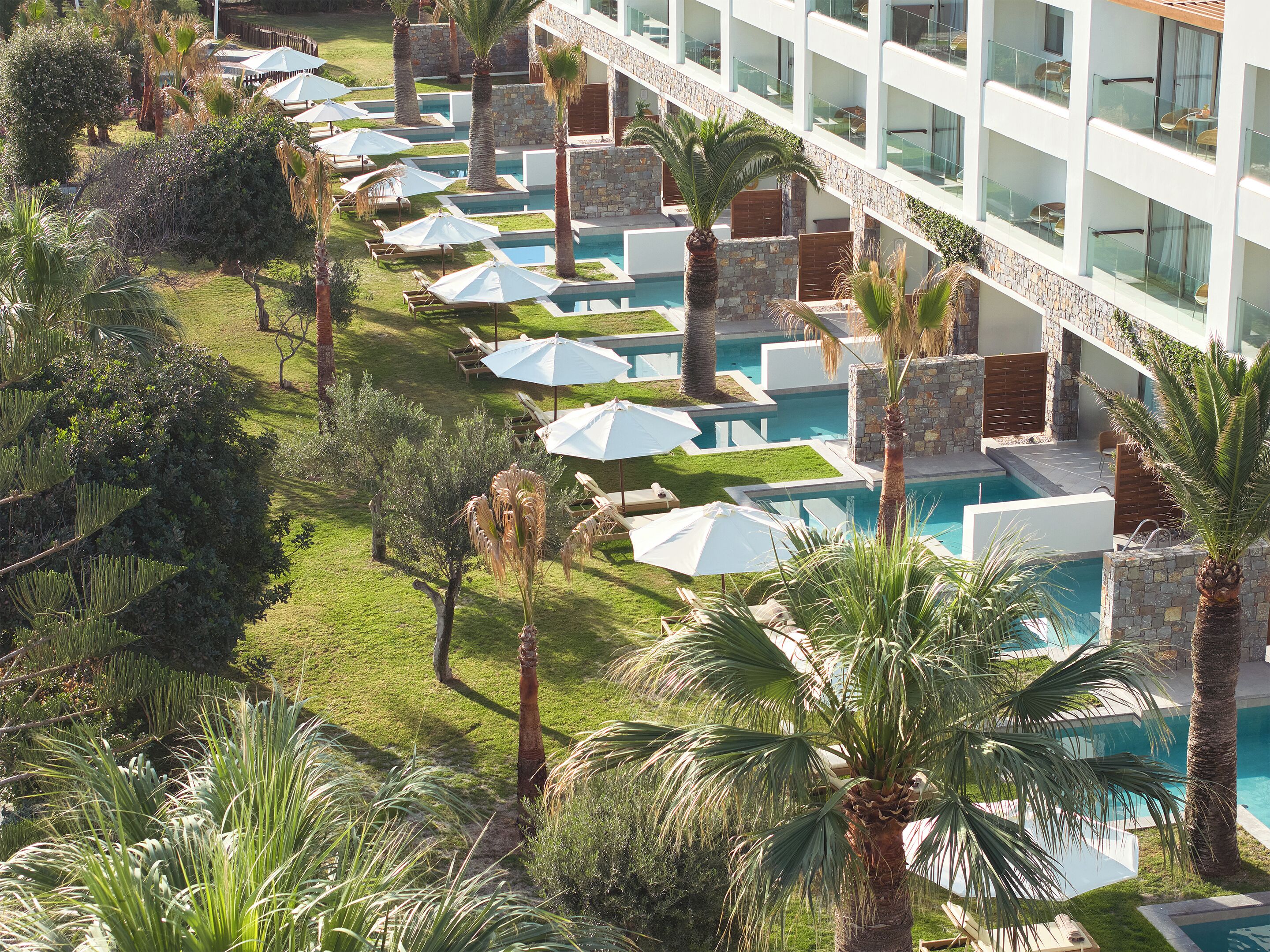 Un resort con varias piscinas, sillas de descanso y palmeras.