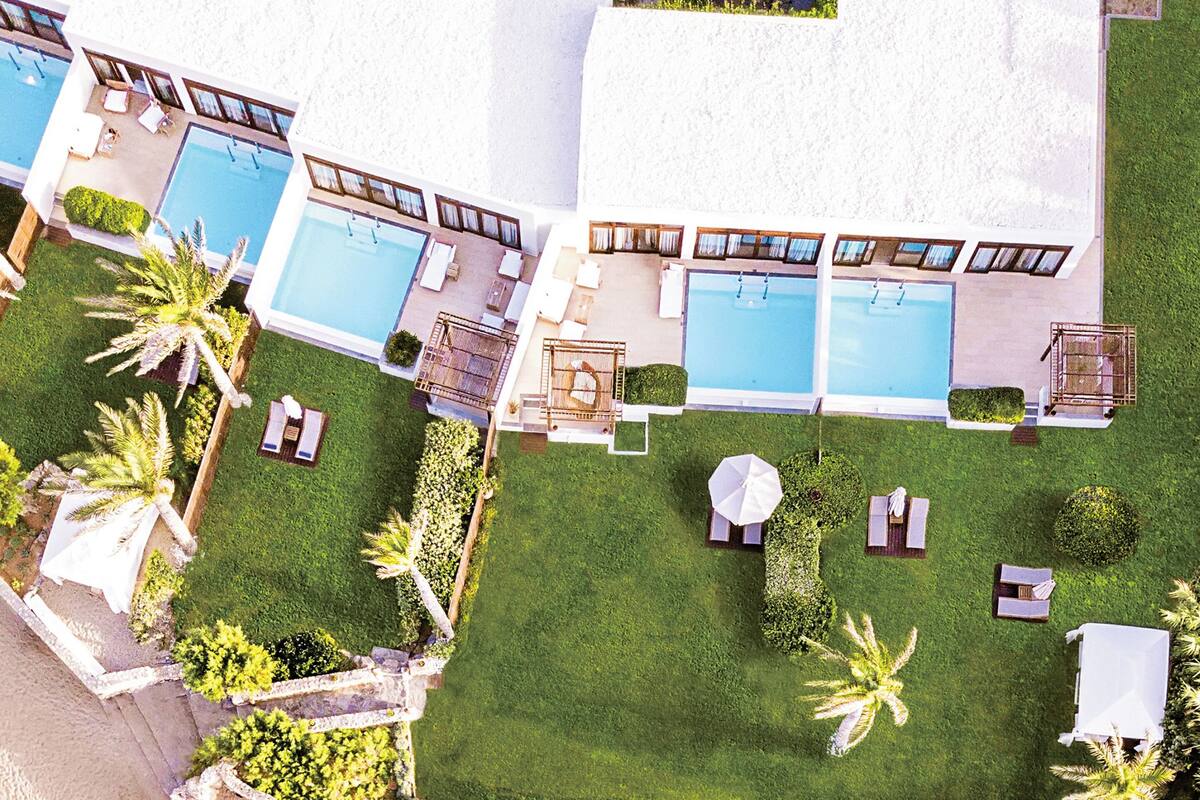 Eine Vogelperspektive auf ein Resort mit mehreren Swimmingpools, Liegestühlen und Palmen.