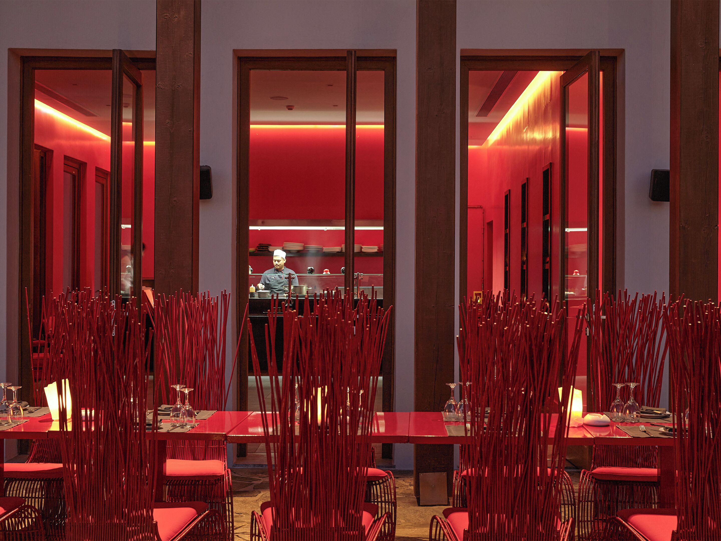 A restaurant with red decor, including chairs and tables, and a visible kitchen area.