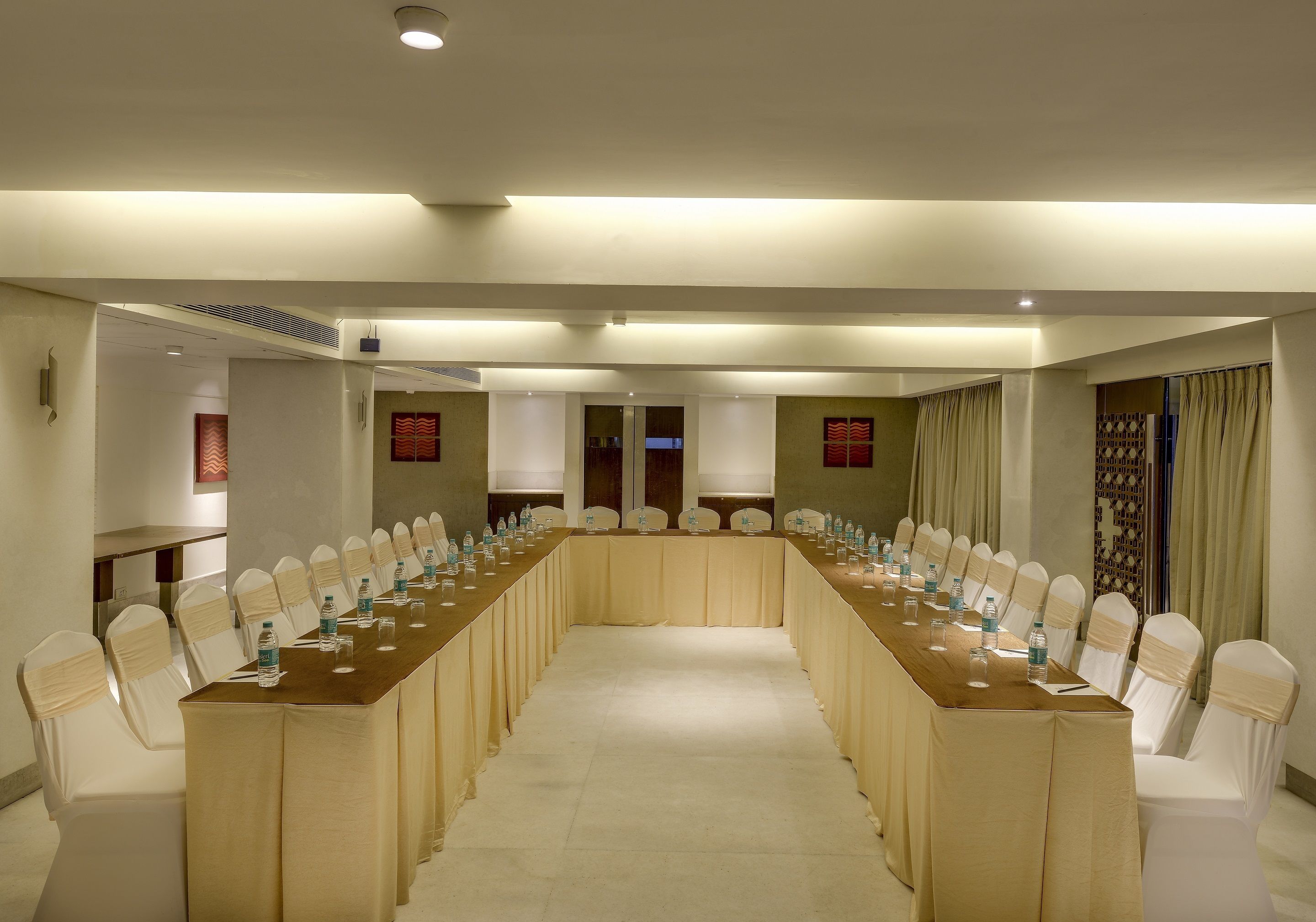 A conference room with a long table and chairs, equipped with water bottles and glasses.
