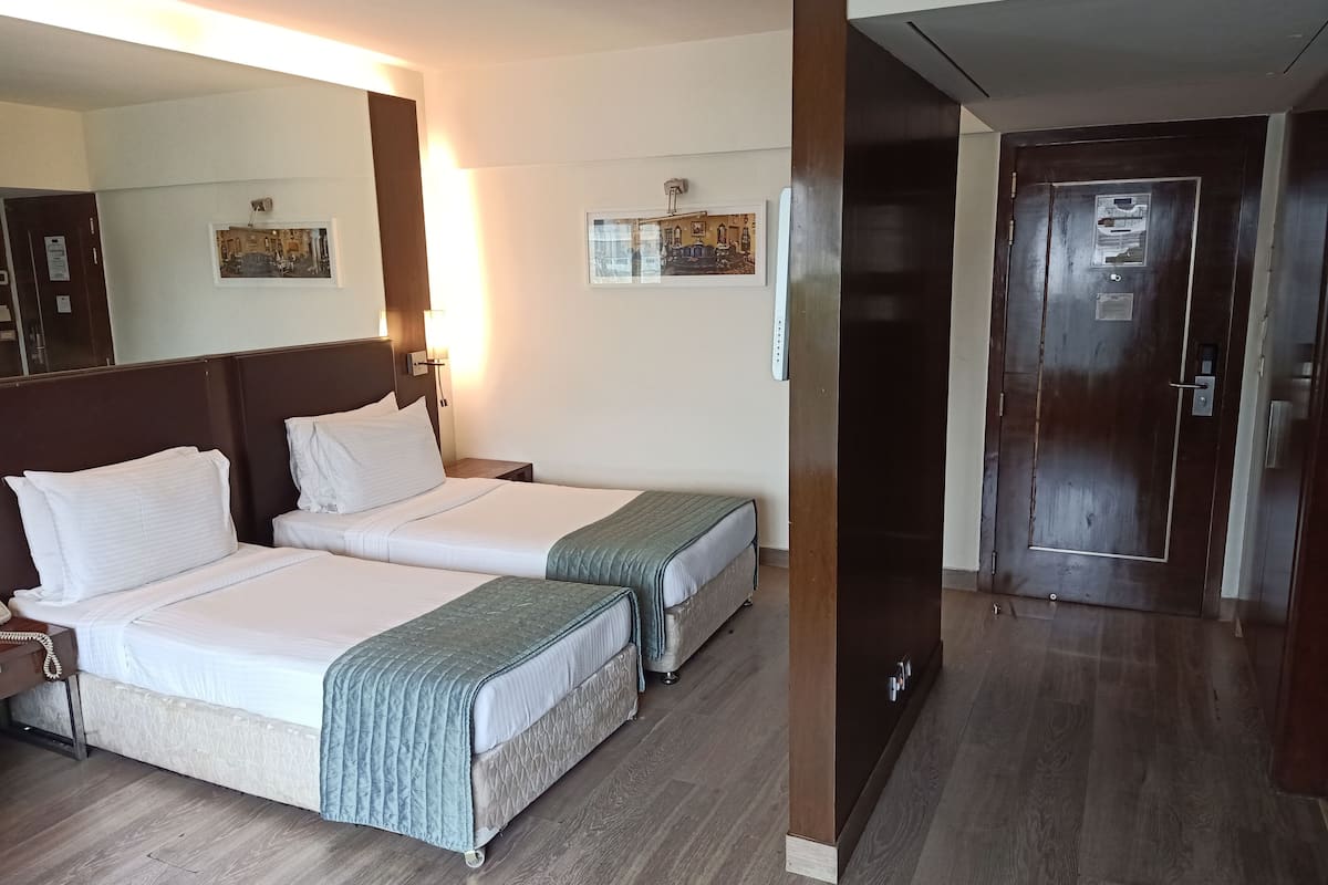 A hotel room with two beds, a large mirror, and a door with a sign.