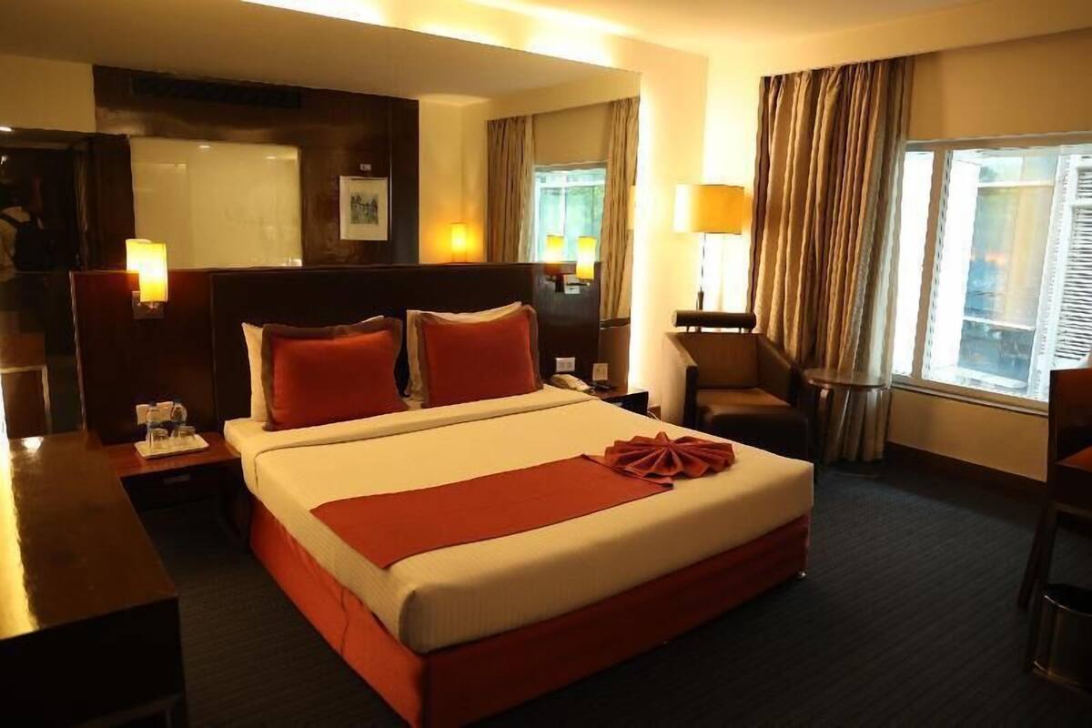 Una habitación de hotel con una cama grande, un escritorio, una silla y una ventana con cortinas.