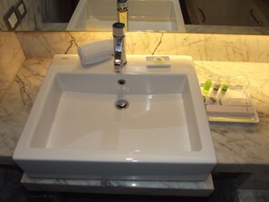 A bathroom with a white sink, a mirror, and toiletries on the counter.