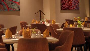 Comedor con mesas dispuestas para varios comensales, con un diseño de interiores moderno y arte abstracto en las paredes.
