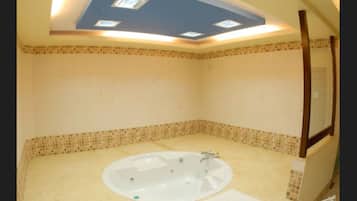 Bathroom features a bathtub, tiled floor and walls, and a skylight.
