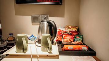 A kitchenette with a kettle, two mugs, a tray with snacks, and a water bottle.