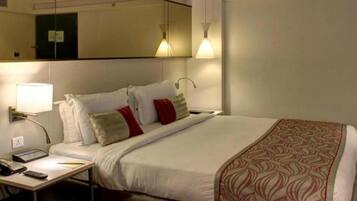 Hotelkamer met een bed, nachtkastje met telefoon en lamp, en een spiegel aan de muur.