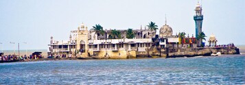 A historic building with a prominent lighthouse and a large dome, situated by the water.