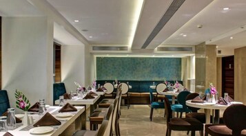 A modern dining area with multiple tables and chairs, a patterned wall, and a clean, well-lit environment.
