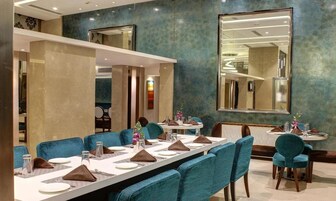 A conference room with a long table set for a meeting, blue chairs, and a large mirror on the wall.
