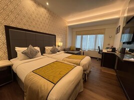 Una habitación de hotel con dos camas, un escritorio, una silla y una ventana con cortinas.