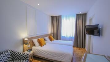 Une chambre d’hôtel avec deux lits, une télévision, une chaise et une table de chevet avec une lampe.