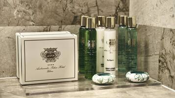 A set of toiletries including a body lotion, a green bottle, and a white bottle, along with a box labeled "Ambassador Palace Hotel."