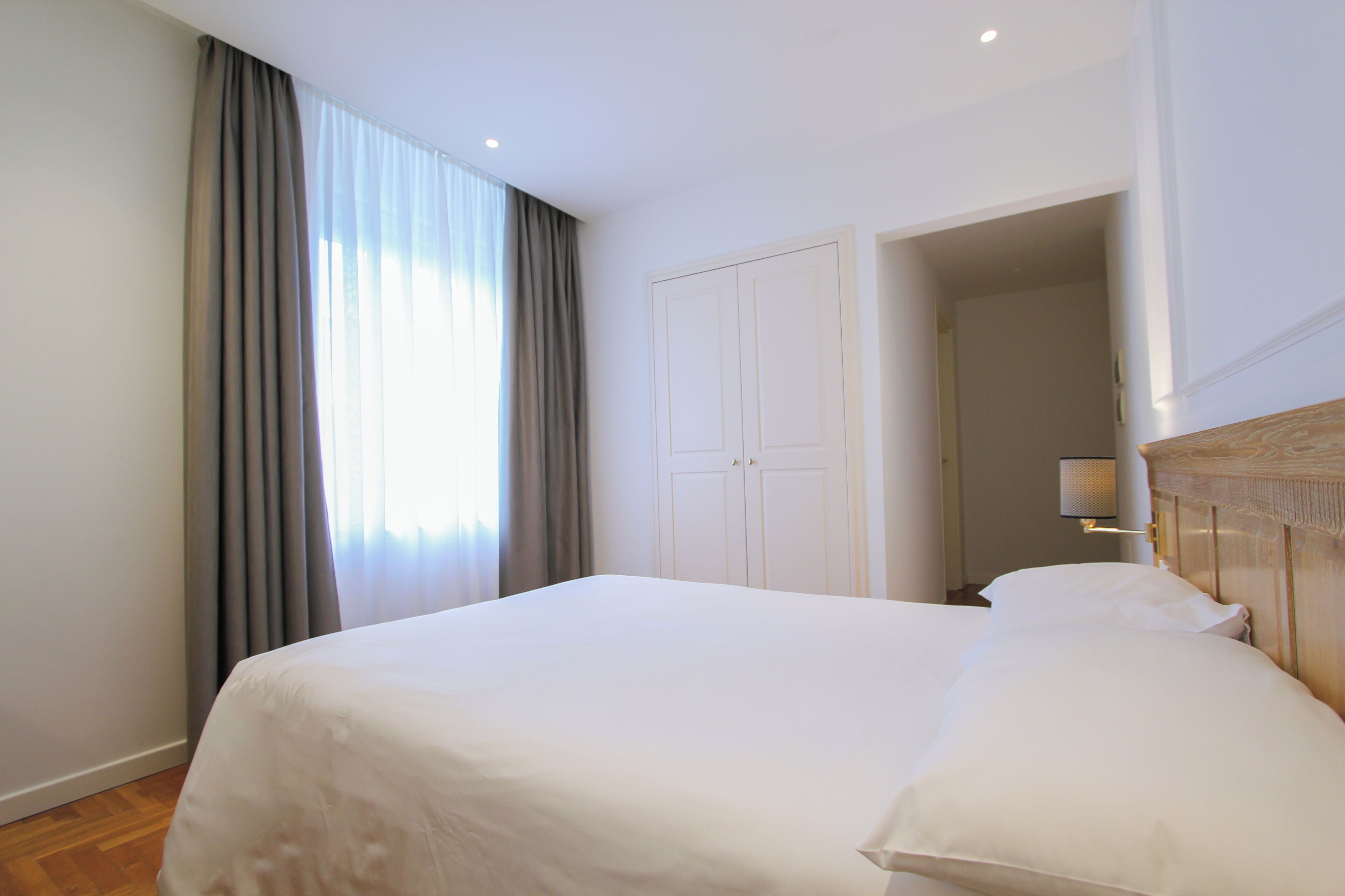Una habitación de hotel con una cama grande, un armario y una lámpara.