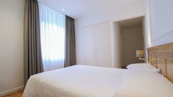 Una habitación de hotel con una cama grande, un armario y una lámpara.