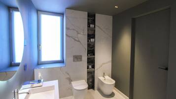 A modern bathroom with a marble vanity, a bidet, and a toilet.