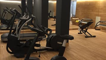Ett gym med olika typer av träningsutrustning, inklusive löpband och motionscyklar, samt trägolv.