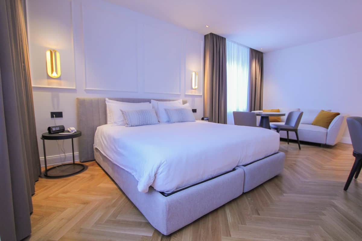 Una habitación de hotel moderna con una cama grande, una mesita, un sofá y una silla.