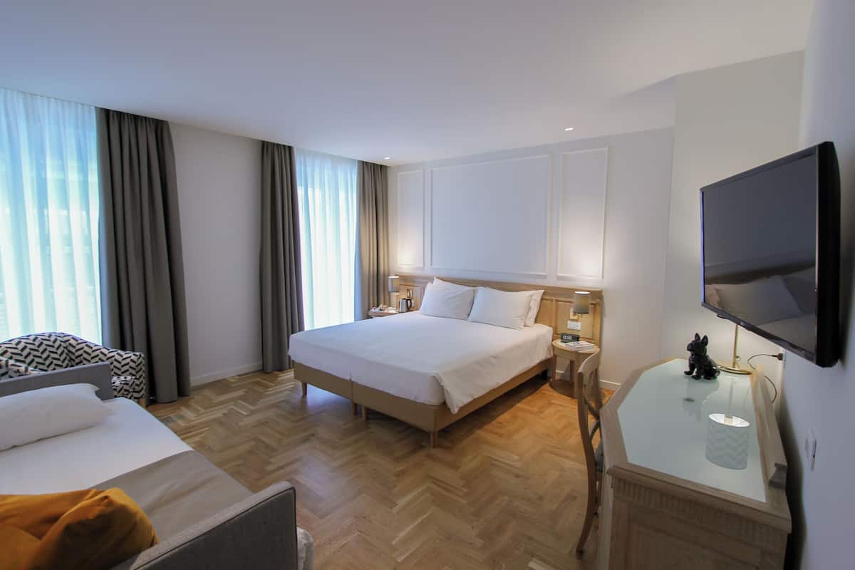Habitación de hotel con una cama grande, un escritorio, un televisor de pantalla plana, una silla y una mesita.