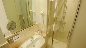 A modern bathroom with a glass-enclosed shower, a sink, and a mirror.