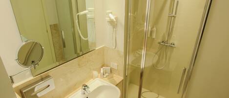 A modern bathroom with a glass-enclosed shower, a sink, and a mirror.