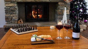 Una mesa de madera con un tablero de ajedrez, una botella de vino y copas de vino tinto.