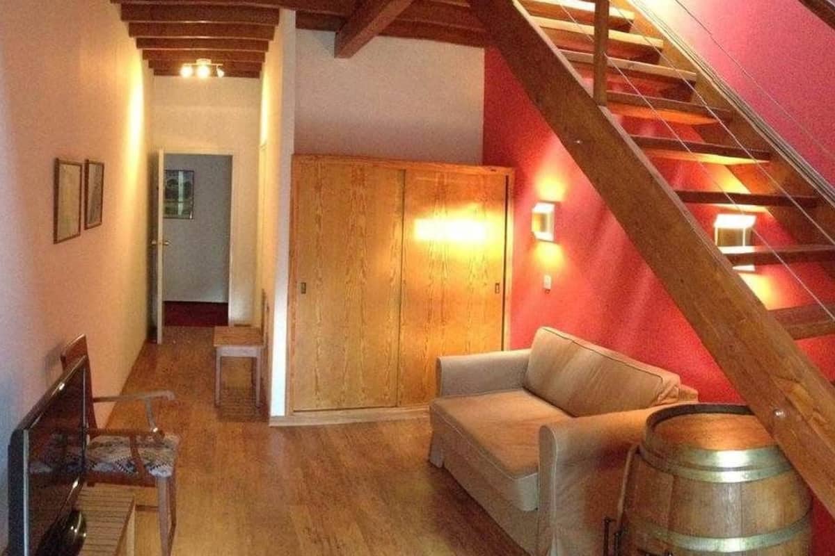 Une pièce chaleureuse avec un escalier en bois, un canapé et une armoire en bois.