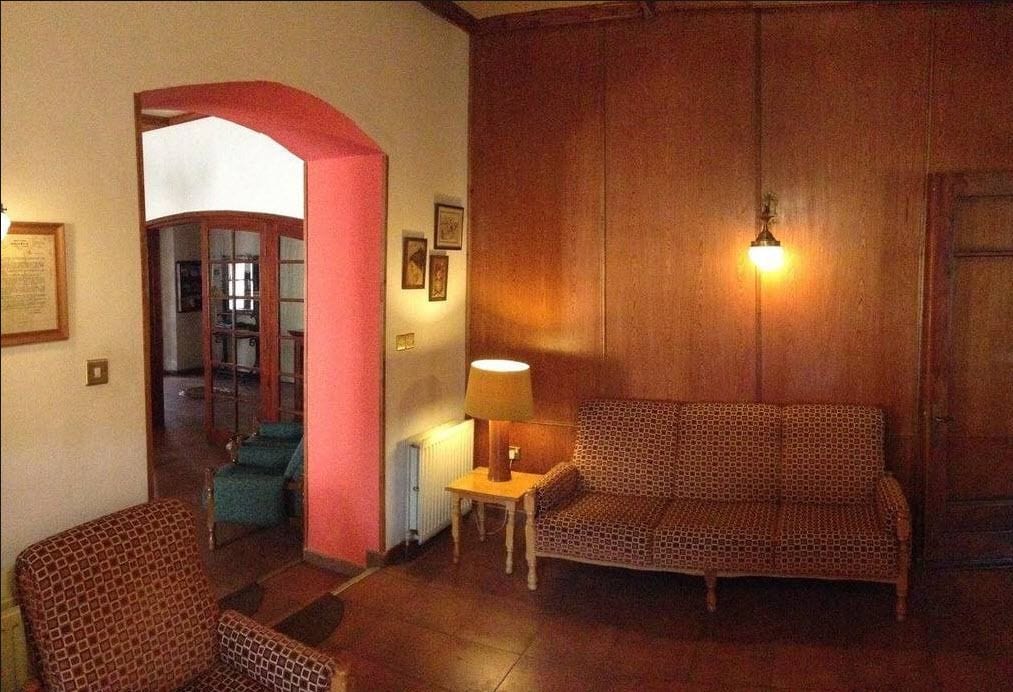 Una sala de estar acogedora con un sofá estampado, una mesita con una lámpara y un sillón.