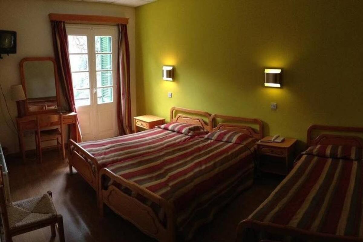 Une chambre avec deux lits, une commode en bois, une chaise et une fenêtre avec des rideaux.